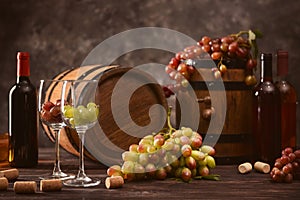 Wooden barrels with ripe grapes, glasses and bottles of wine on table