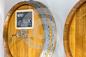 Wooden barrels for wine with a tap in wine shop. Close-up. Wine for bottling. Price for one liter wine. side view