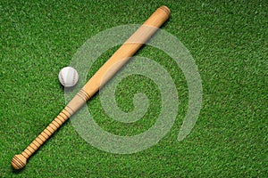 Wooden baseball bat and ball on green grass, flat lay. Space for text