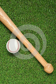 Wooden baseball bat and ball on green grass, flat lay. Sports equipment