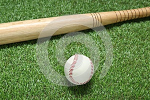 Wooden baseball bat and ball on green grass. Sports equipment