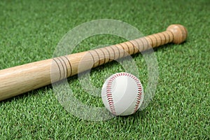 Wooden baseball bat and ball on green grass. Sports equipment