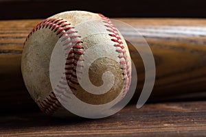 A wooden baseball bat and ball on a wooden background