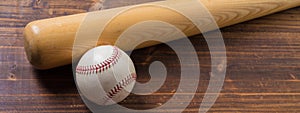 A wooden baseball bat and ball on a wooden background