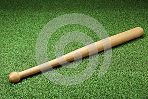 Wooden baseball bat on green grass, above view. Sports equipment