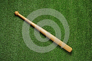 Wooden baseball bat on green grass, top view. Sports equipment