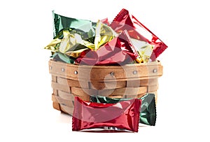A Wooden Basked Filled with Foil Wrapped Chocolate Truffles Isolated on a White Background