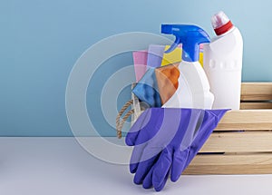 Wooden basket with cleaning products on a blue background with space for text