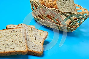 Wooden basket full of square pieces of bread with seeds for toast lies on blue table on kitchen