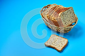 Wooden basket full of square pieces of bread with seeds for toast lies on blue table on kitchen