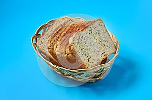 Wooden basket full of square pieces of bread with seeds for toast lies on blue table on kitchen
