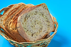 Wooden basket full of square pieces of bread with seeds for toast lies on blue table on kitchen