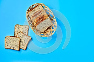 Wooden basket full of square pieces of bread with seeds for toast lies on blue table on kitchen