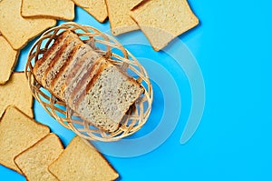 Wooden basket full of square pieces of bread with seeds and vanilla for toast lies on blue table on kitchen