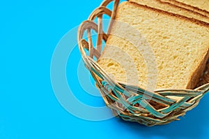 Wooden basket full of square pieces of yellow vanilla bread for toast lies on blue table on kitchen