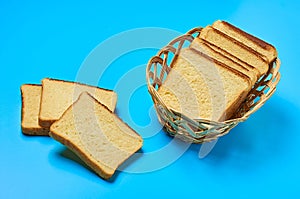 Wooden basket full of square pieces of yellow vanilla bread for toast lies on blue table on kitchen