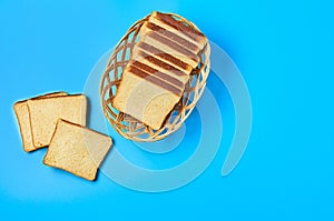 Wooden basket full of square pieces of yellow vanilla bread for toast lies on blue table on kitchen