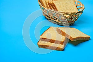 Wooden basket full of square pieces of yellow vanilla bread for toast lies on blue table on kitchen