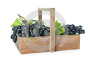 Wooden basket with ripe sweet grapes on white background
