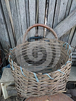 A wooden basket or sepet against a wooden building in the village during the day. Handmade pannier