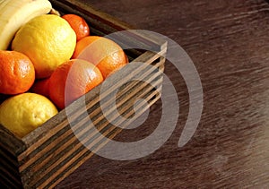 Wooden basket with tropical fruits. Juicy mandarins, orange, lemon and banana. Sweet vitamin ripe fruits.