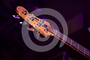 Wooden bass guitar fretboard in purple concert light