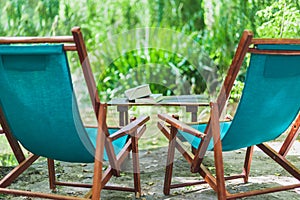 Wooden beach chairs in the garden and some books on the table. Relaxing place concept