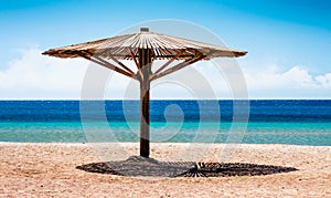 Wooden beach umbrella on the shore without people of the Red Sea in Egypt