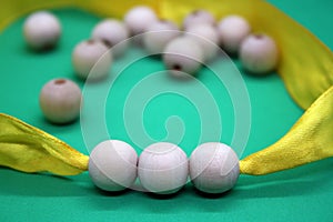 Wooden beads and yellow ribbon on a green background
