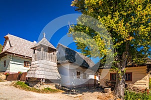 A wooden bell tower on a street with ancient colorful houses