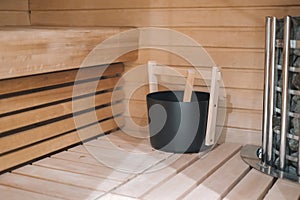 A wooden bench with a black bucket on it. The bucket is filled with water and a wooden stick.