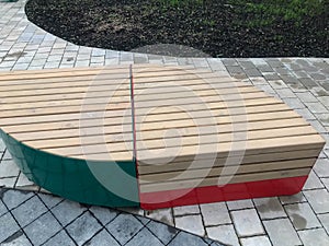 A wooden bench in the center of the residential complex in the form of a droplet. seating area with red and green color. wooden