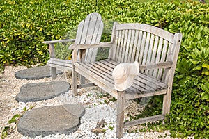 Wooden bench and chair with a hat left on the arm