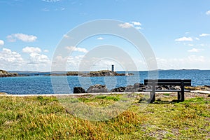 Wooden bench on the coastal shoreline in Inishbofin with the lighthouse on Gun Rock and a sailboat in the background photo