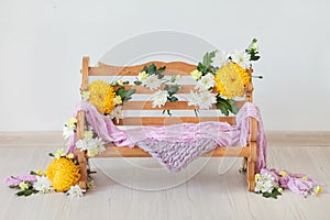 A wooden bench decorated with yellow and white chrysanthemums flowers