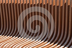 Wooden bench element, brown curved slats with rounded edge. Abstract background