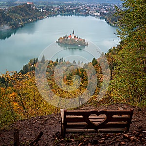 Wooden bench with fantastic view to the famous alpine Bled lake Blejsko jezero, amazing autumn landscape, outdoor travel