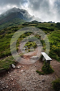 Wooden bench at the foot of a misty mountain