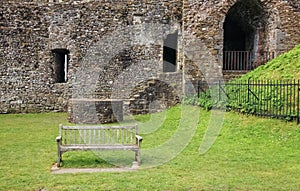 A wooden bench in front of medieval wall ruins