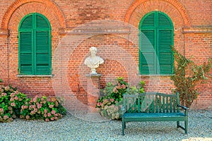 Wooden bench in front of red brick house in Italy.