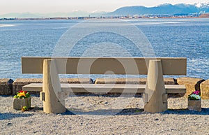 Wooden bench in front of the sea. Beautiful view of the mountains in the background