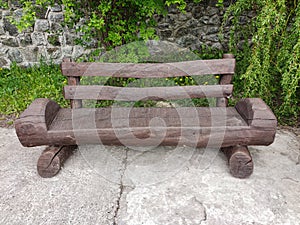 Wooden bench handmade from wooden painted log stands in the park