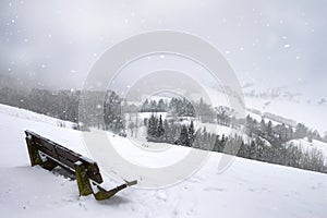 Wooden bench on a hill and snowfall