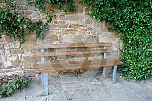 Wooden bench beside an ivy-clad sandstone wall