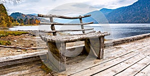 Wooden bench on a lake pier in the mountains