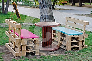 Wooden bench made of pallets for sitting with table made from coil of electric cable
