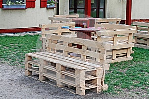 Wooden bench made of pallets for sitting with tables made from coil of electric cable