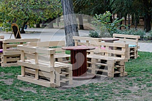 Wooden bench made of pallets for sitting with tables made from coil of electric cable
