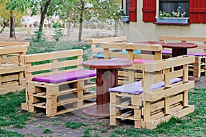 Wooden bench made of pallets for sitting with tables made from coil of electric cable