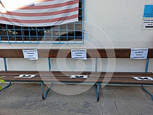 Wooden bench marked with Social Distancing sticker at 1 meter distance for Novel Corona Virus prevention